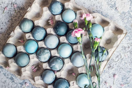 Blue Easter eggs with pink flowers. Easter composition on grey concrete background. Natural ecological staining with food coloring. Top view.の写真素材