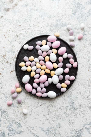 Easter composition with mini chocolate eggs in pastel colors on grey concrete background. Happy Easter Holidays. Top view. Copy space.の写真素材