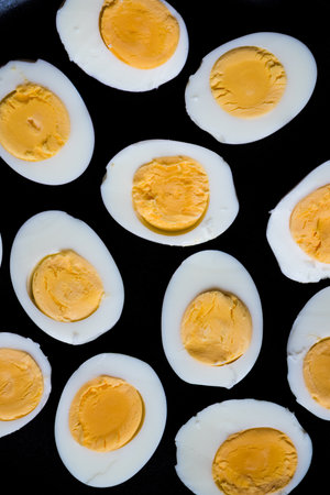 Boiled eggs pattern on a black background viewed from above. Top view. Egg half. Yolk. Fresh farm...