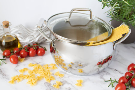 Stainless pot with lid and vegetables and pastaの写真素材