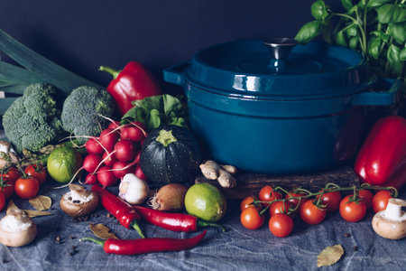 Cast iron pot and vegetables on rustic table. Homemade food, cooking, vegetarian conceptの写真素材