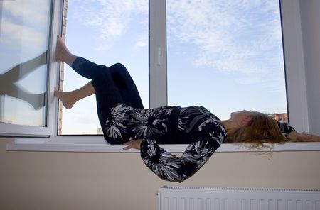 The girl lays at a window and looks in the skyの写真素材