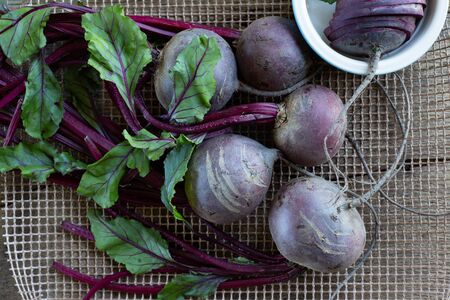Bunch of fresh, spring, organic beetroot on kitchen grid, with slices of beetroot in ceramic plate...