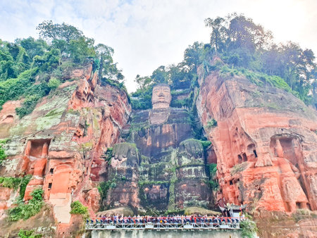 the Leshan giant buddha is carved out from the side of the mountain beside the riverの写真素材