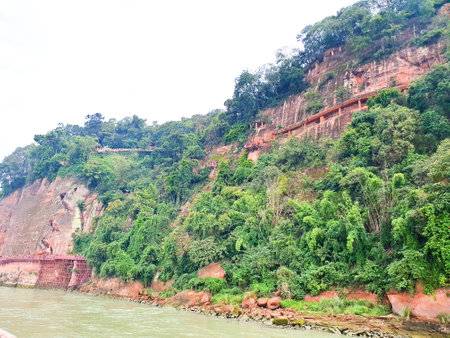 the giant buddha is carved out from the side of the mountain beside the riverの写真素材