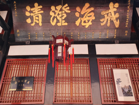 Traditional Chinese lantern with intricate design and red tassels hanging from a wooden ceiling in a historic architectural setting.の写真素材