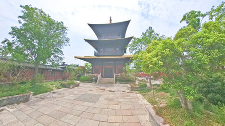 A traditional multi-tiered Chinese pagoda stands elegantly amidst lush greenery, with stone steps...