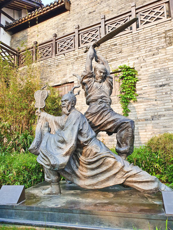 A dynamic bronze statue of two ancient warriors in action, one kneeling with a fan, one mid-strike with swordの写真素材