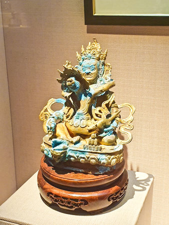 A detailed statue of a multi-faced deity with many arms, standing gracefully on a lotus pedestal in a museum.の写真素材