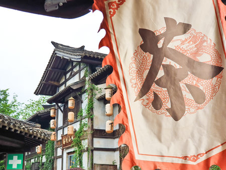 Traditional Chinese tea house with wooden architecture, hanging lanterns, outdoor seating, and cobbled stone path surrounded by lush greeneryの写真素材