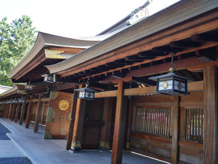 A close-up shows a row of traditional hanging lanterns with circular crests, suspended beneath deep brown wooden eavesの写真素材