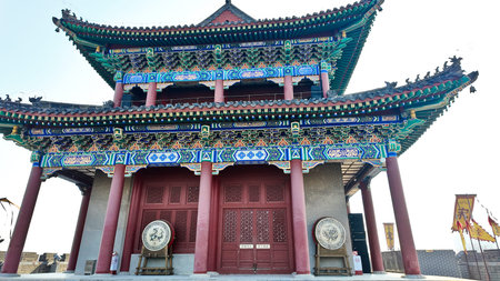 Ornate traditional Chinese gate tower with layered roofs, colorful painted brackets, red columns,...