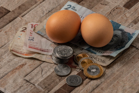 Eggs, Colombian pesos and coins on a wooden backgroundの写真素材