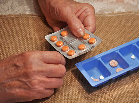 elderly woman holding a pill in her hand