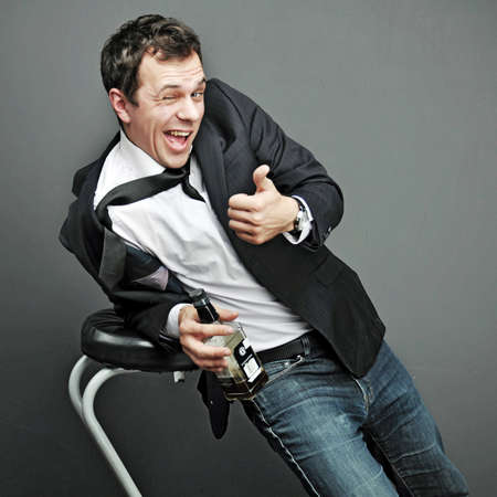 Drunk young man in office clothes with a bottle of alcohol
