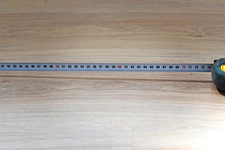 carpenter's tape measure on wooden floor closeupの写真素材