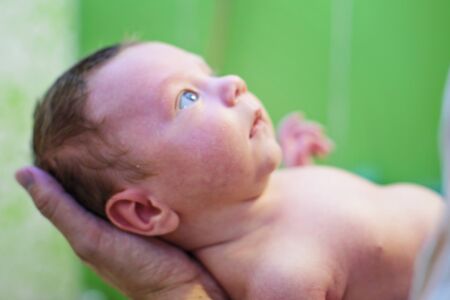 newborn baby on hands at the father