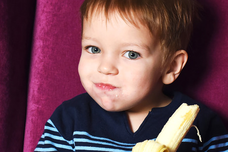 handsome little boy eating banana close upの写真素材