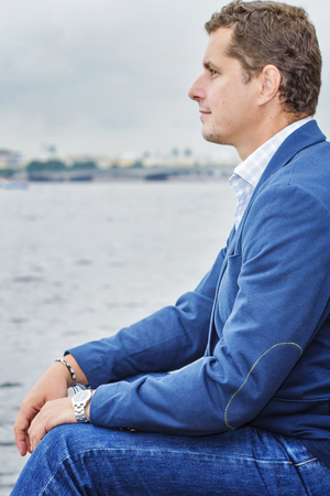 young man sits near the waterの写真素材