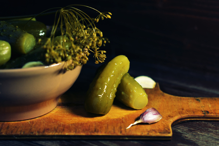 Pickled cucumbers on a wooden Board. Pickles, traditional Russian snack. Dark background.の写真素材
