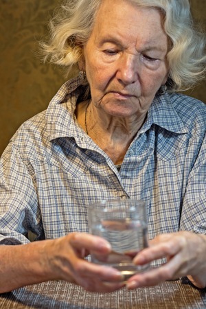 old women's hands holding glass of waterの写真素材