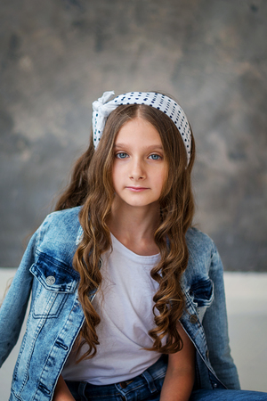Girl model sitting on a red chair, gray backgroundの写真素材