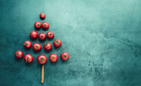Creative layout of Christmas tree branches made of real cherry tomatoes on a tinted background. Concept Of the new year of nature. Flatley.の写真素材