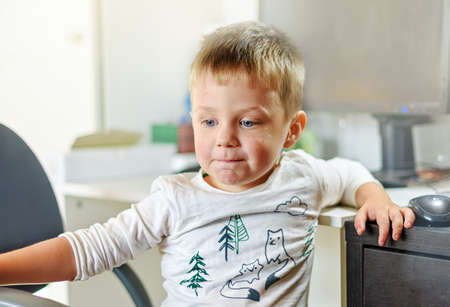 cute little boy playing at the computer at home