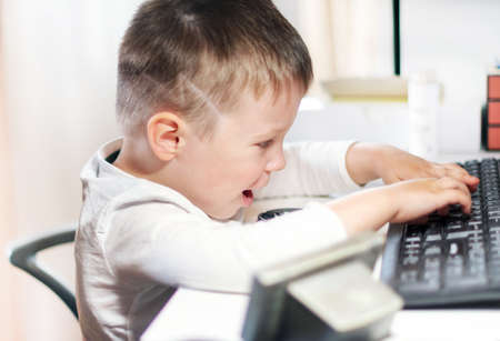 cute little boy playing at the computer at home