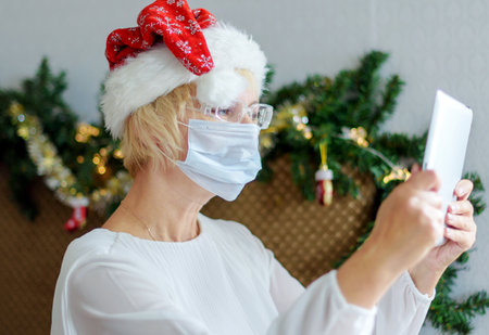Christmas online congratulations. Smiling woman using mobile tablet for video call friends and parents.の写真素材