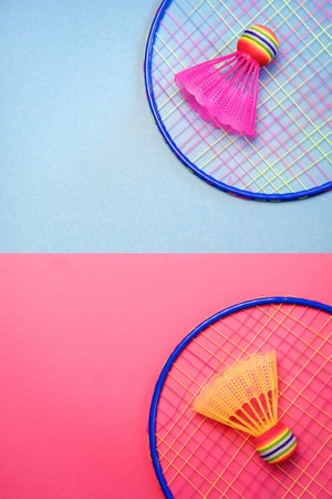 Colored badminton shuttlecock and racket on a blue and pink background. Concept: minimalism, summer...