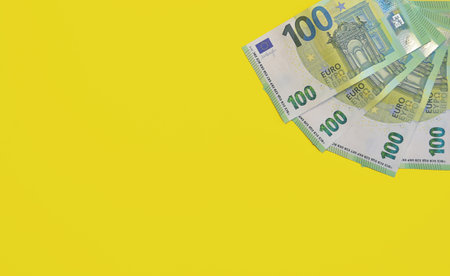 Banknotes of 100 Euro. European currency banknotes isolated on a yellow background. Close-up view from above. The concept of the European Unions economic crisis.の写真素材