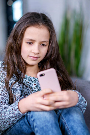Happy teenage girl checks social networks while holding a smartphone in her hands. A young...