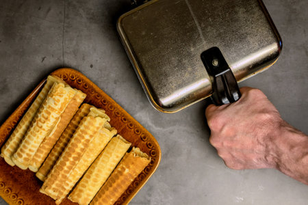 Cooking waffles at home - a waffle iron, a man's hand holding a pen. Ready-made waffles on a plate....