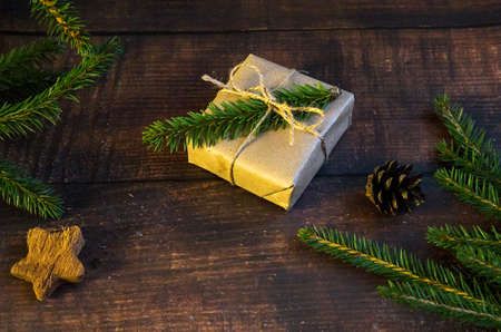 Craft gift box with Christmas tree branch on wooden background