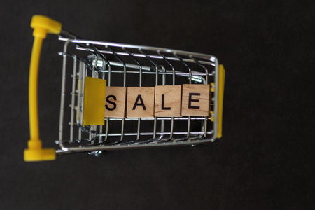 Season of sales in online stores. Cart and sales word on dark blue background. Creative idea for a sale, promotion, or concept for cyber Monday or black Fridayの写真素材