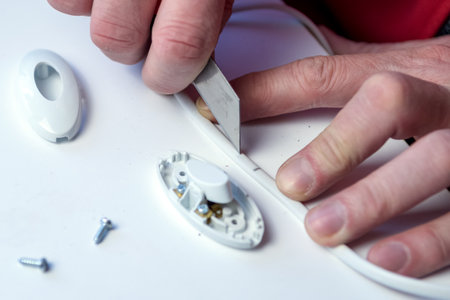 Working male electrician prepares an electric cord to install a light switch in the apartment. The...
