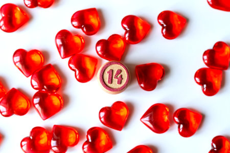 Festive background: a lot of red hearts on a white background, lying randomly and the number 14 in the middle. Small stones in the shape of a heartの写真素材