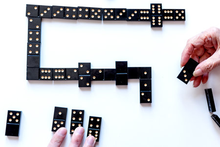Family entertainment for a fun leisure game of dominoes. Grandson and grandmother play dominoes. The view from the top.の写真素材