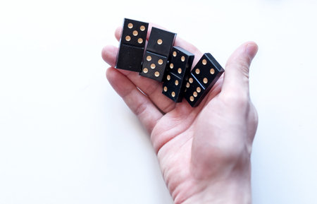 Family entertainment for a fun leisure game of dominoes. The young man's hand holds a domino in his handsの写真素材