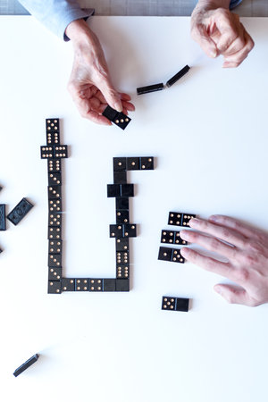 Family entertainment for a fun leisure game of dominoes. Grandson and grandmother play dominoes. The view from the top.の写真素材