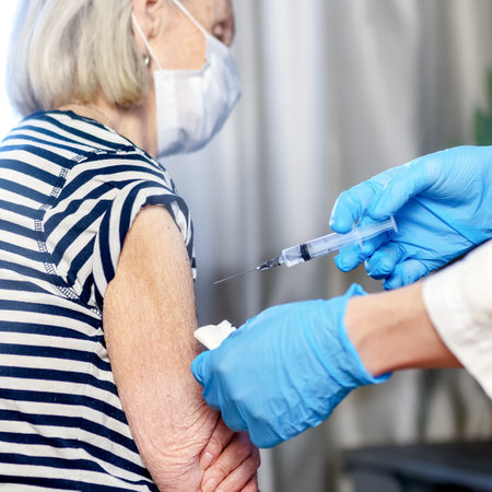 85-year-old woman receives the covid-19 vaccine from a doctor at home. Vaccination of the elderly. An elderly woman is vaccinated against COVID-19 in a nursing home.の写真素材