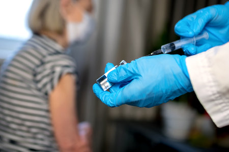 85-year-old woman receives the covid-19 vaccine from a doctor at home. Vaccination of the elderly. An elderly woman is vaccinated against COVID-19 in a nursing home.の写真素材