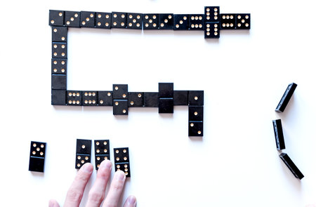 Family entertainment for a fun leisure game of dominoes. The young man's hand holds a domino in his handsの写真素材
