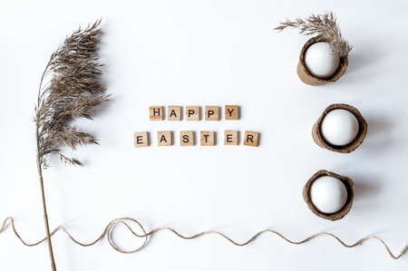 Ecological concept with Easter white eggs with pampas grass and happy Easter inscriptionの写真素材