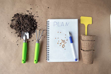 Preparation for planting seeds at home. A notebook with a record of the landing plan. Garden objects on the table top view.の写真素材