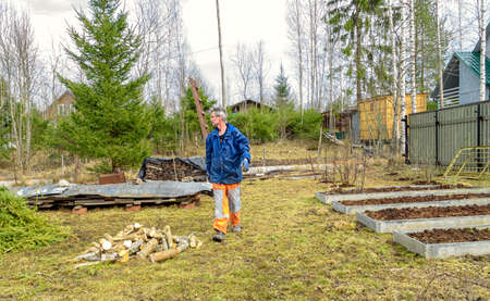 Man on his land plot is preparing for the gardening season in the spring. Empty beds are being...