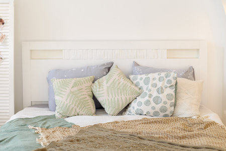 Headboard is a white wooden bed with lots of pillows in a trendy style. Restful sleep