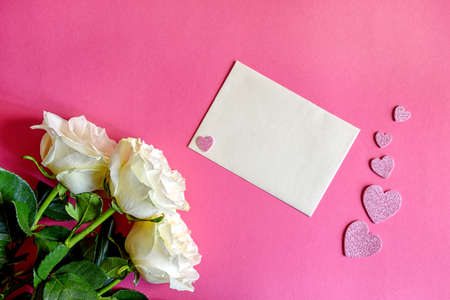 Postcard with three white roses on a pink background with hearts. Greeting card with the concept of flowers. Holiday greeting card. Top view, flat lyingの写真素材