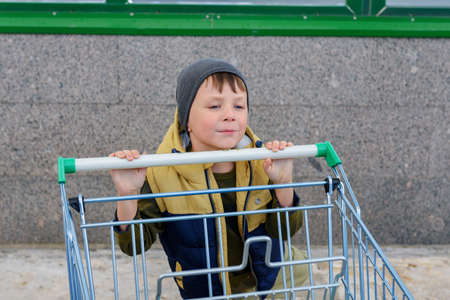 Kid boy pushing empty shopping cart at parking lot.の写真素材